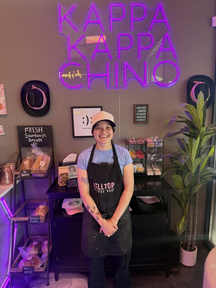 Hilltop Coffee Shop June employee of the month, smiling in front of the Kappa Kappa Chino neon sign